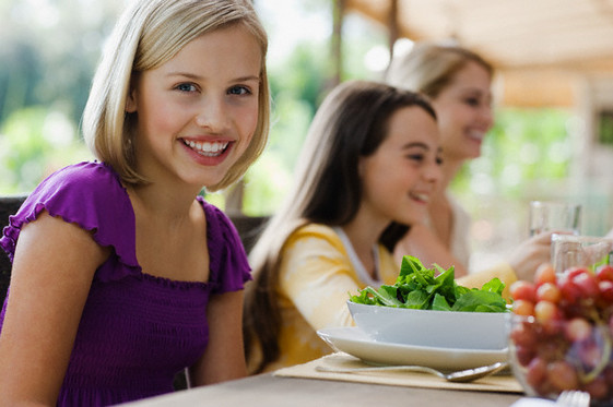 Teenage girl eating dinner with family --- Image by © Laura Doss/Corbis